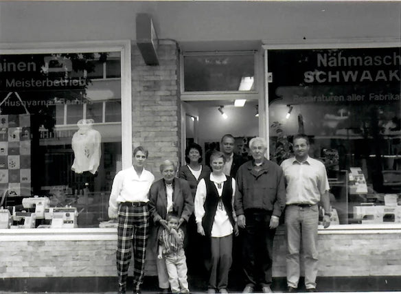 Historisches Foto: Familie Schwaak vor dem Ladengeschäft, im Schaufenster die Schriftzüge Meisterbetrieb und Reparaturen aller Fabrikate